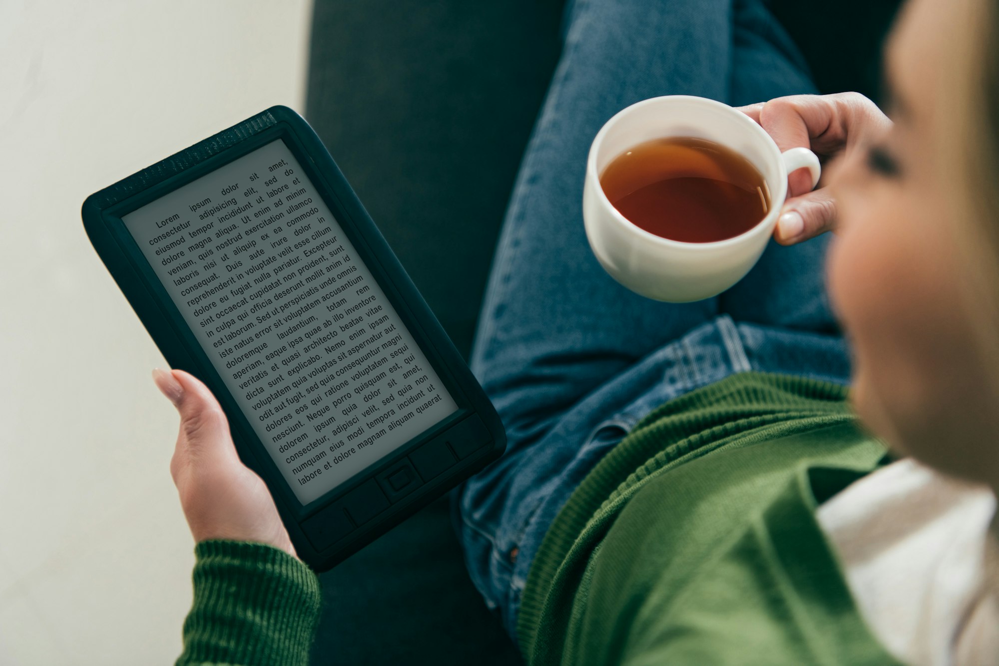 selective focus of woman holding ebook and cup with tea in hands